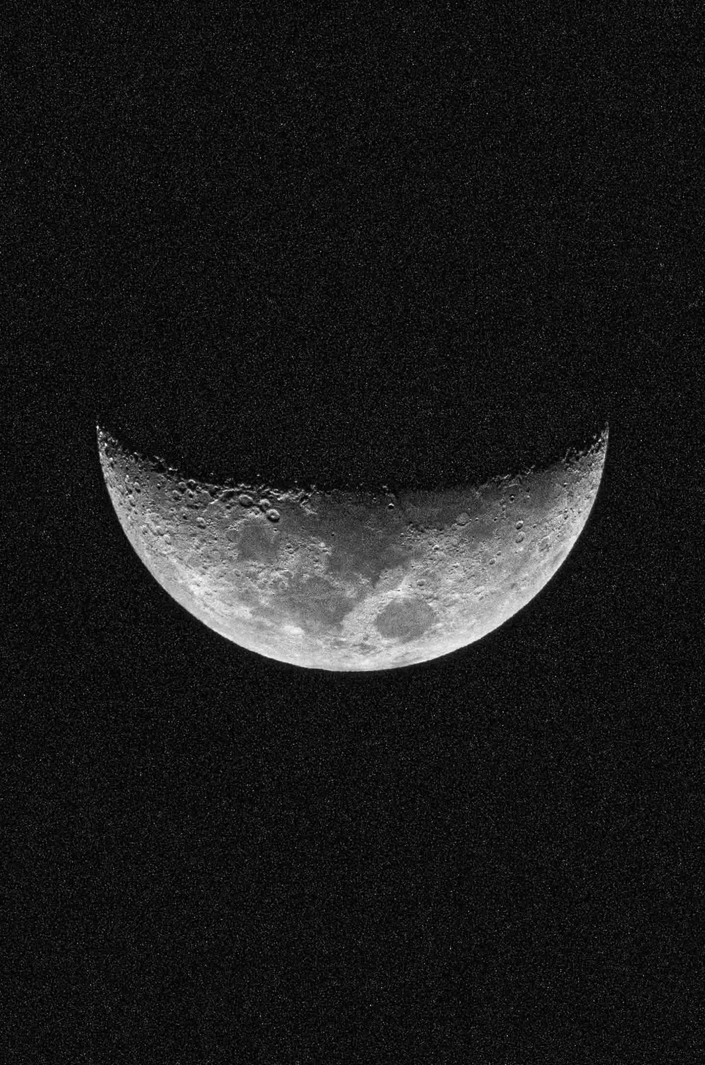 Black and white crescent moon against a dark textured sky